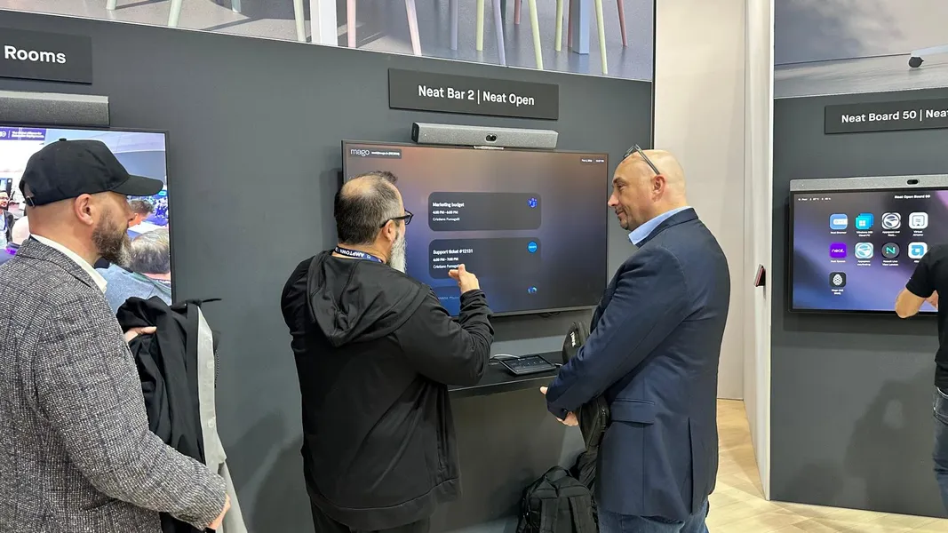 Visitors interacting with the Mago meeting interface on a Neat Bar 2 at ISE 2026