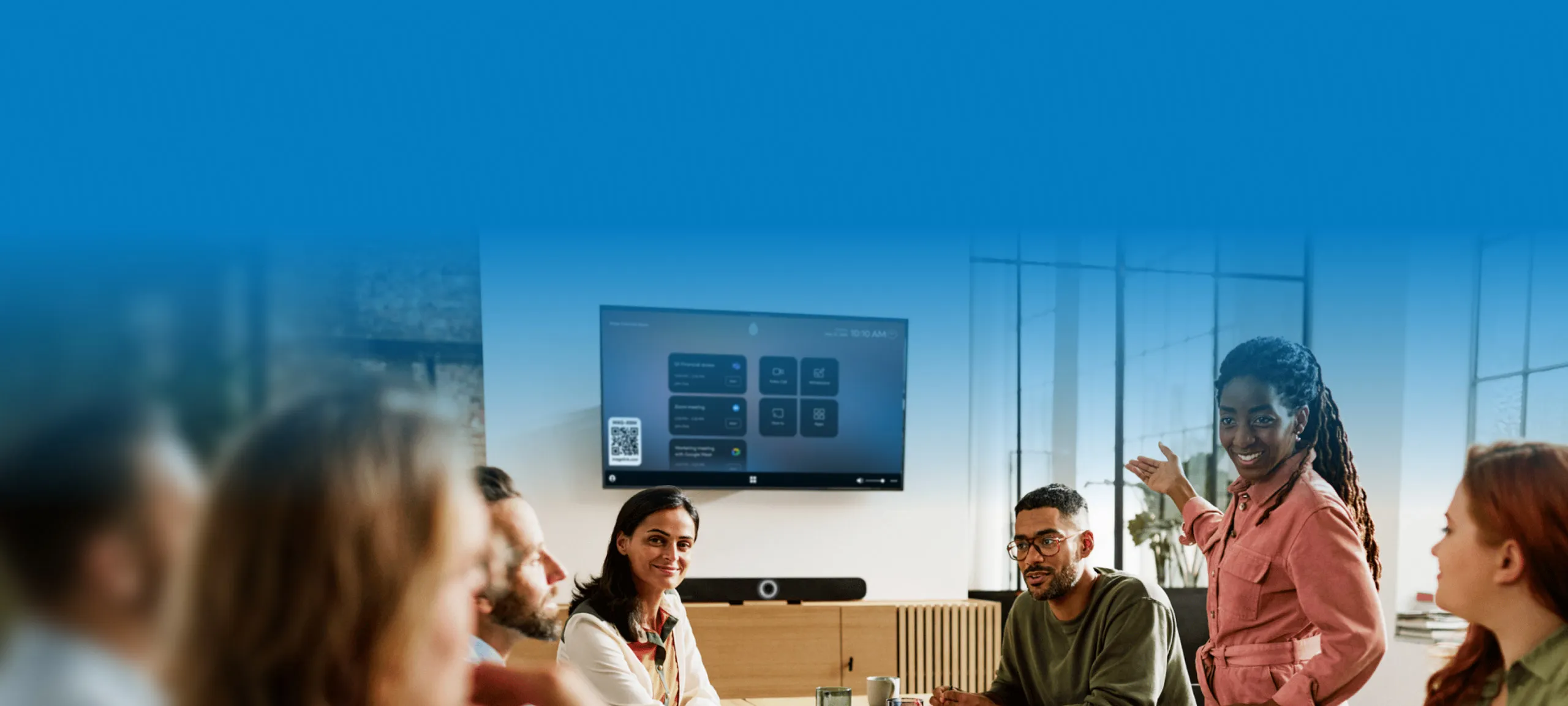 A team meeting around a display with a Sennheiser TeamConnect Bar running Mago